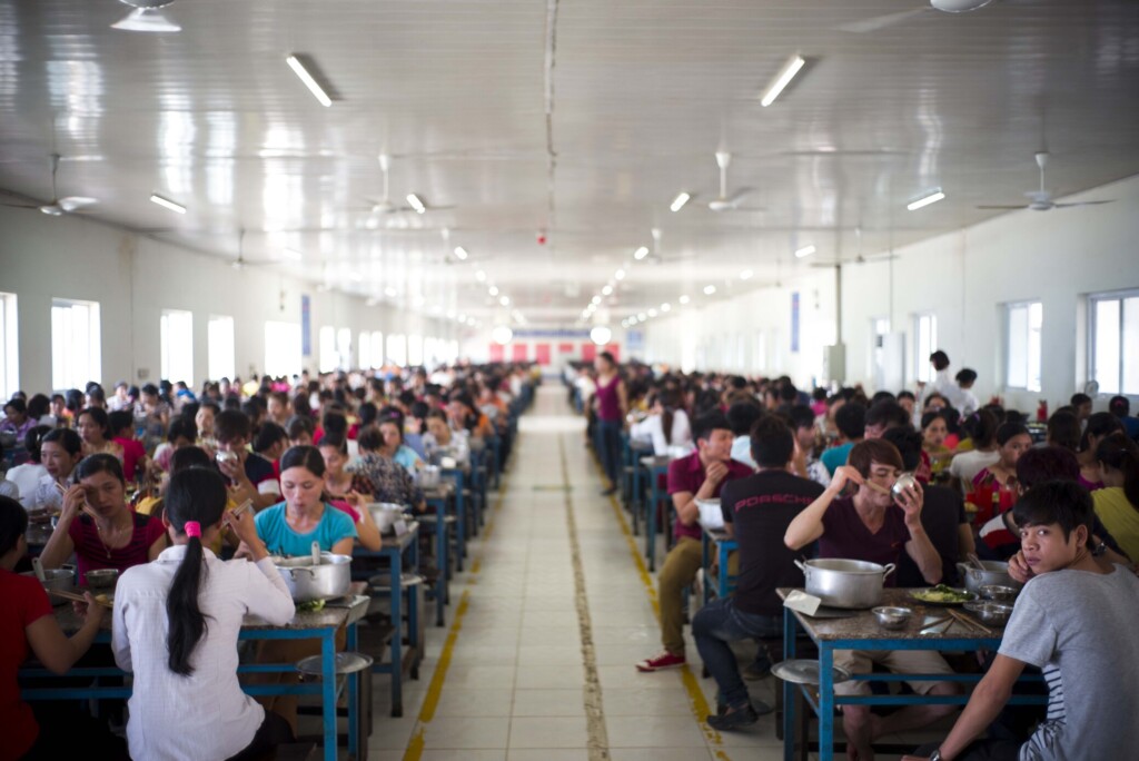 Des ouvriers et ouvrieres déjeunent dans le réfectoire de leur usine au Vietnam.