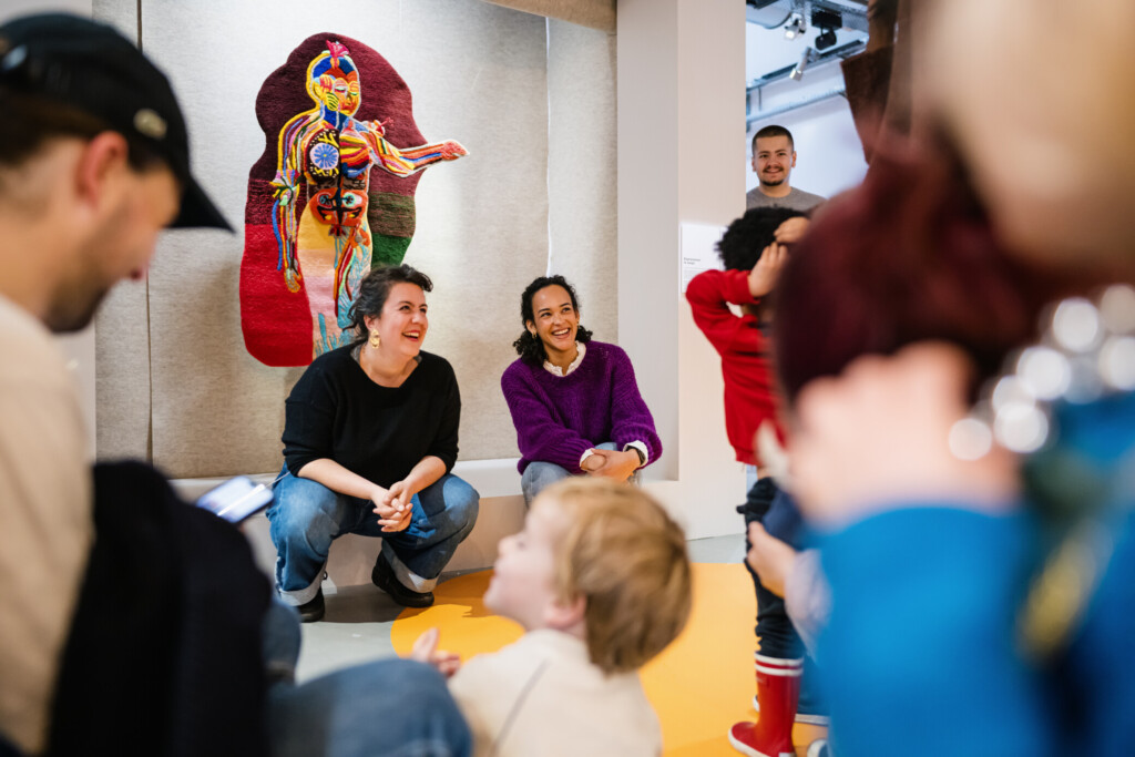 Public et mediation familiale devant l'oeuvre AnatomIAde Roxane Andres au sein de l'exposition collective Faisons Corps au MAIF Social Club a Paris en 2024.